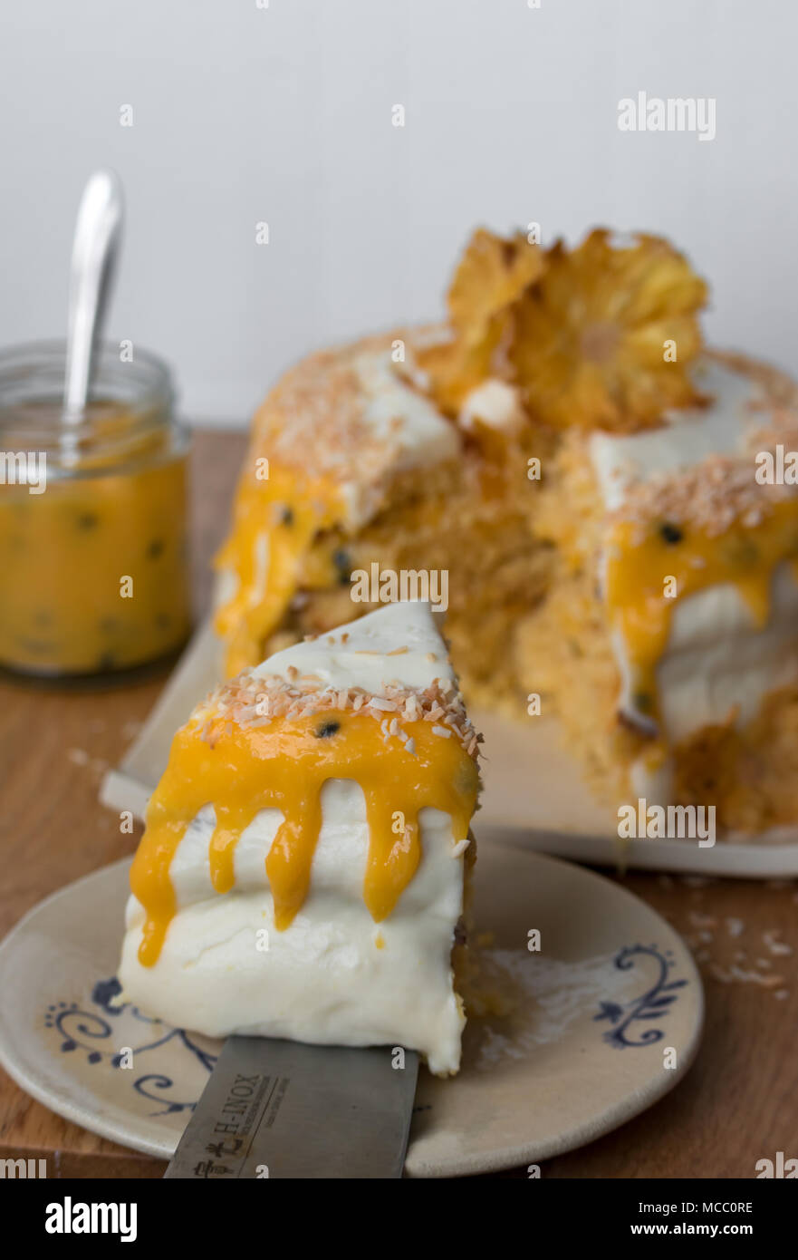 A slice of pineapple coconut layer cake with passion fruit sauce. Served on handmade plate. Stock Photo