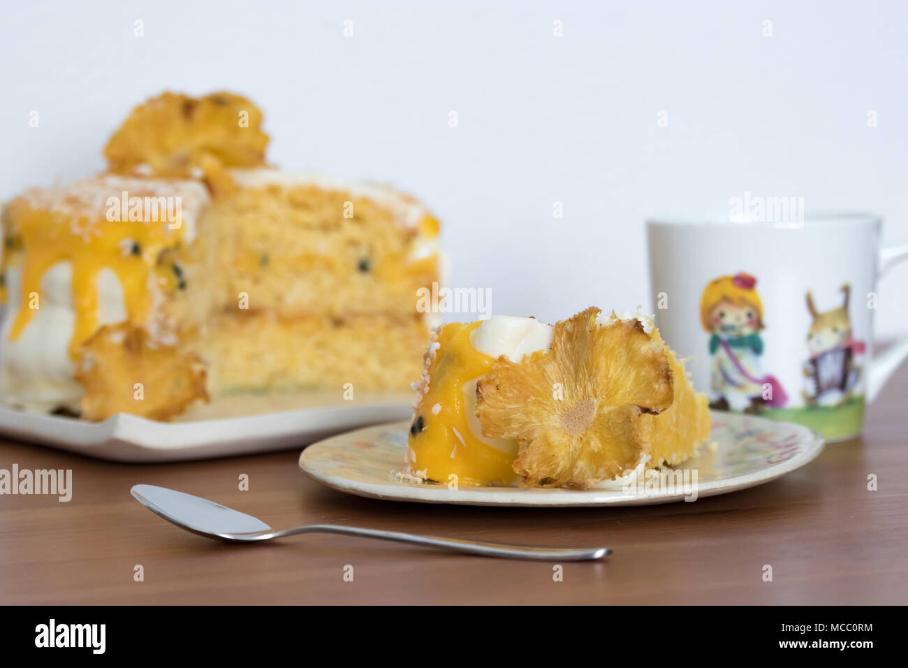 Afternoon tea. A slice of pineapple and coconut layer cake with passion fruit curd. Served on handmade plates. Stock Photo