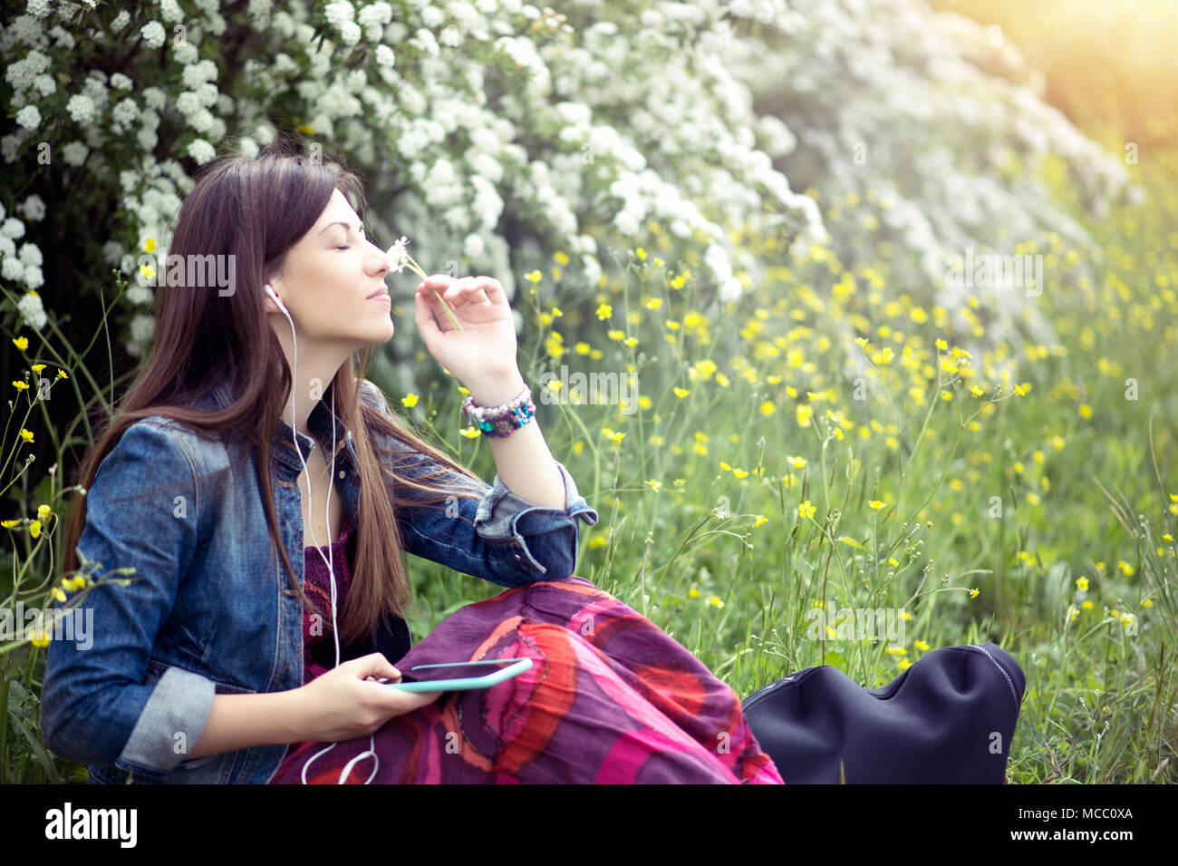 Woman relax with headphones listening to music sitting on grass spring outdoors Stock Photo