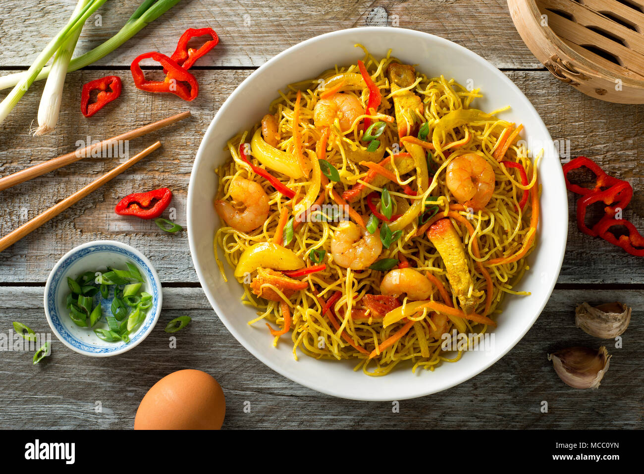 Delicious Singapore style noodles with curry, shrimp, bbq pork, carrots, red pepper, onion and scallions. Stock Photo