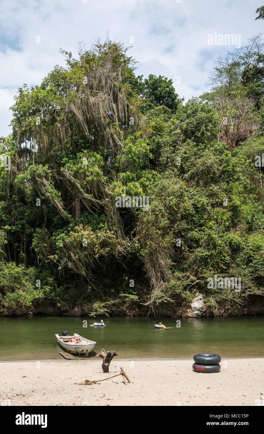 Tourist family tubing along a river with lush green forest. Colombia, South America. Stock Photo