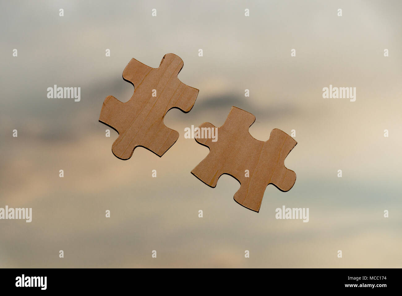 Putting puzzle pieces together on sky background with sunlight Stock