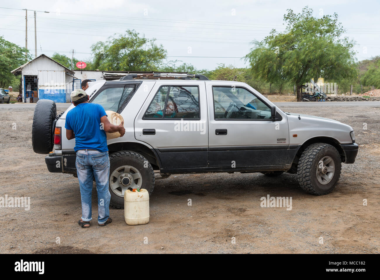 A man fills up gasoline for a car at a rural petro station. Colombia, South America. Stock Photo
