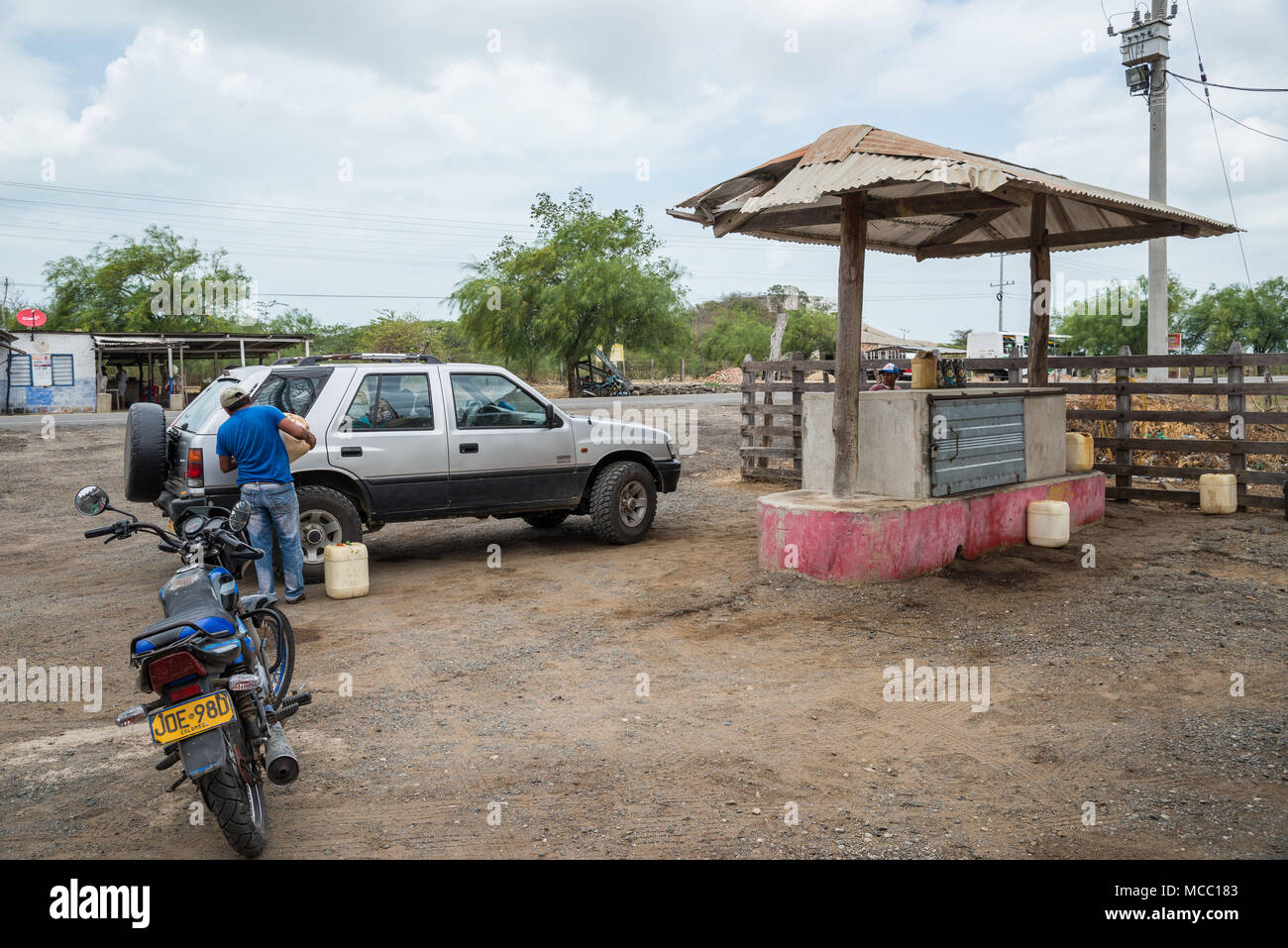 A man fills up gasoline for a car at a rural petro station. Colombia, South America. Stock Photo
