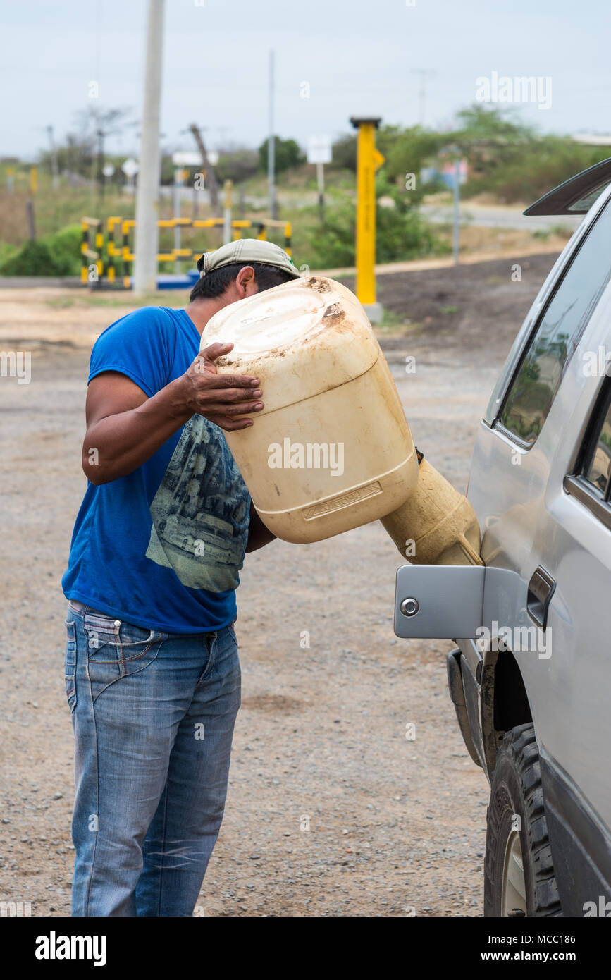 A man fills up gasoline for a car in a rural petro station. Colombia, South America. Stock Photo