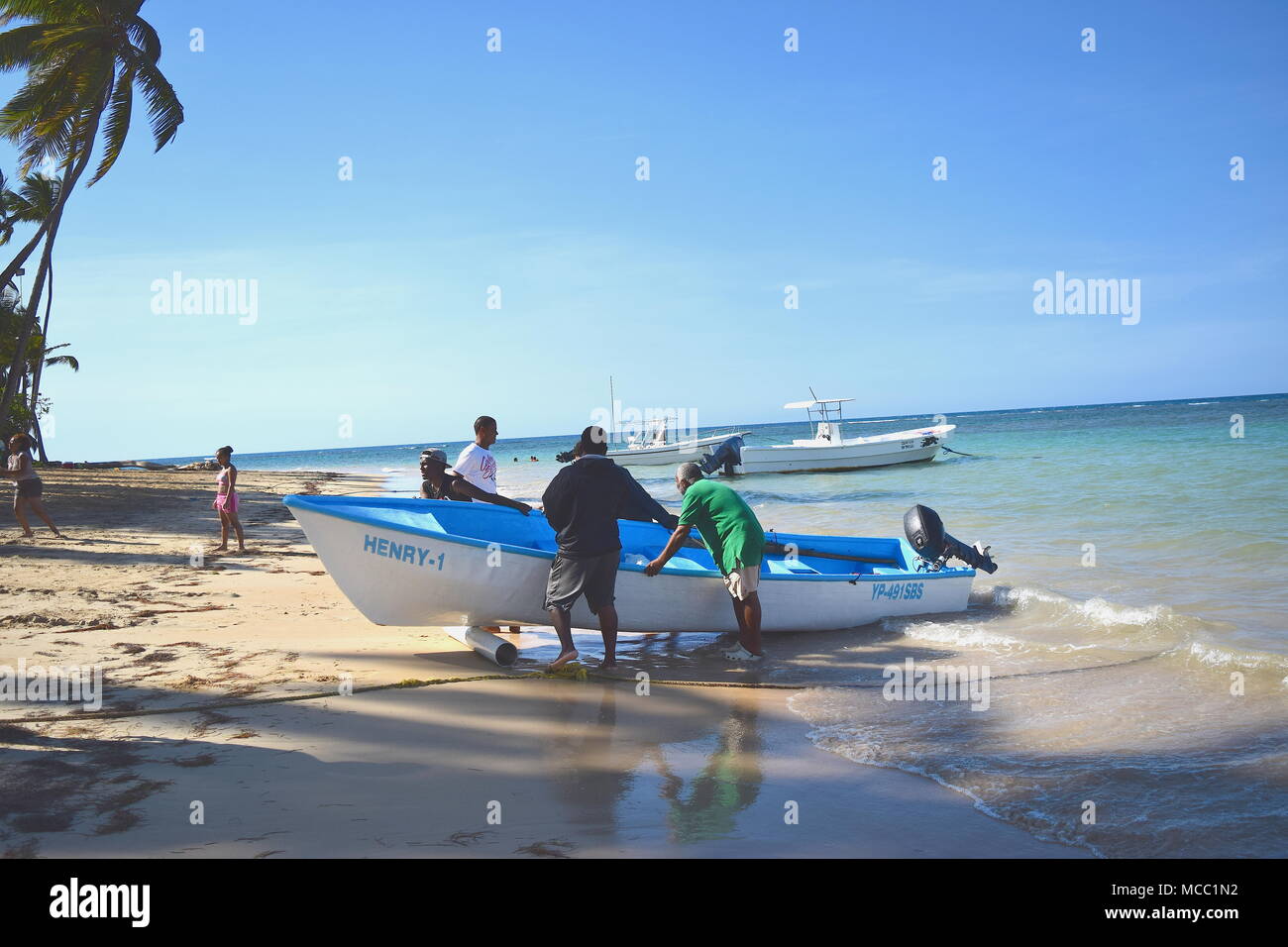 Men taking out a motorboat from the ocean in Dominican Republic Stock Photo