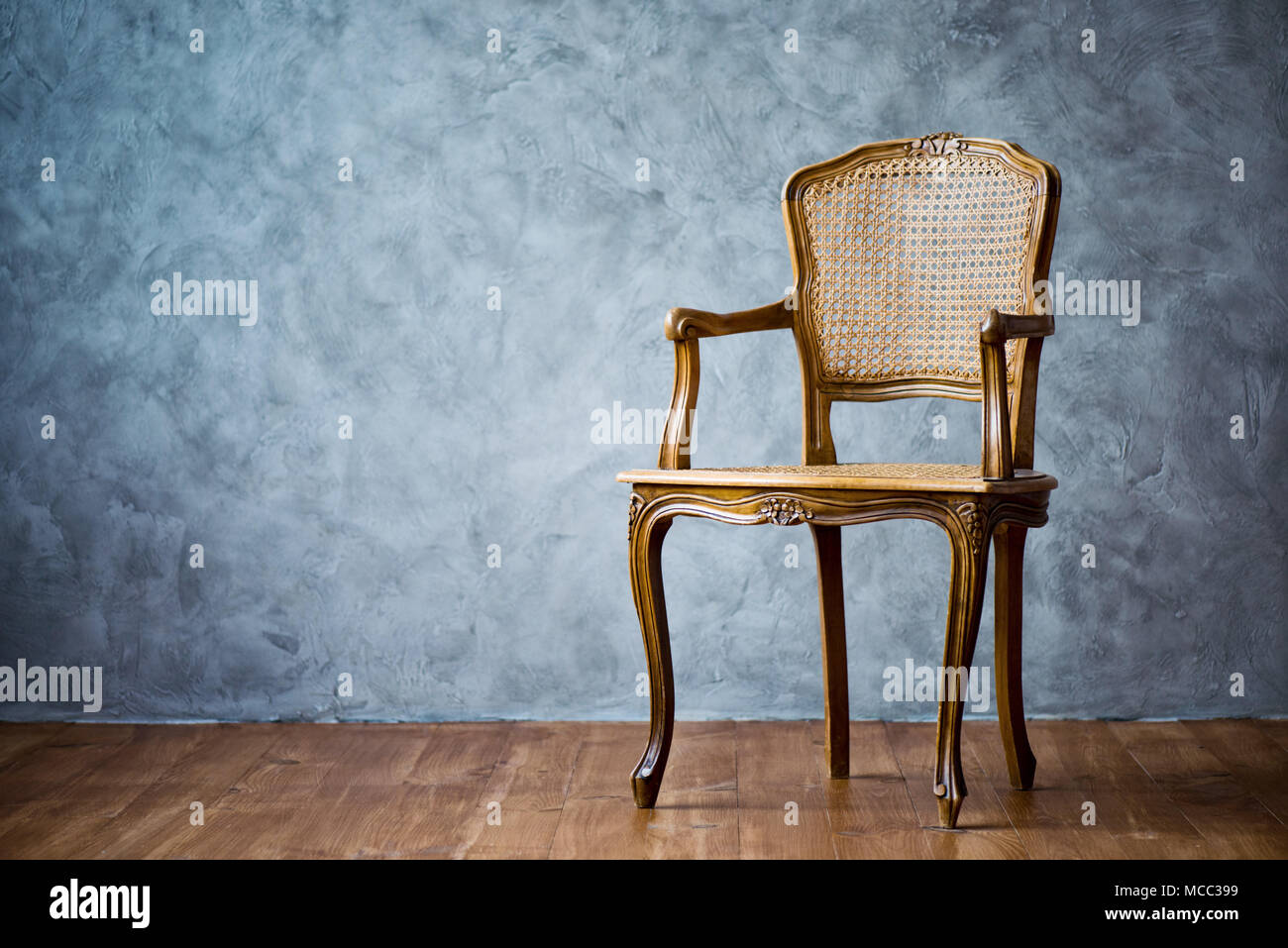 old chair on a gray wall background Stock Photo - Alamy