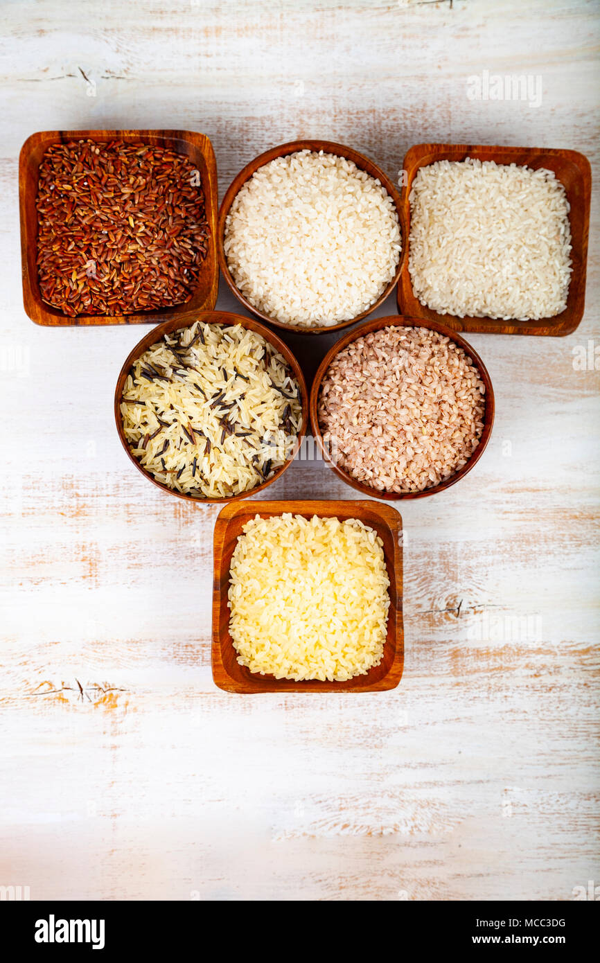 Six bowls with different varieties of rice on a wooden background ...