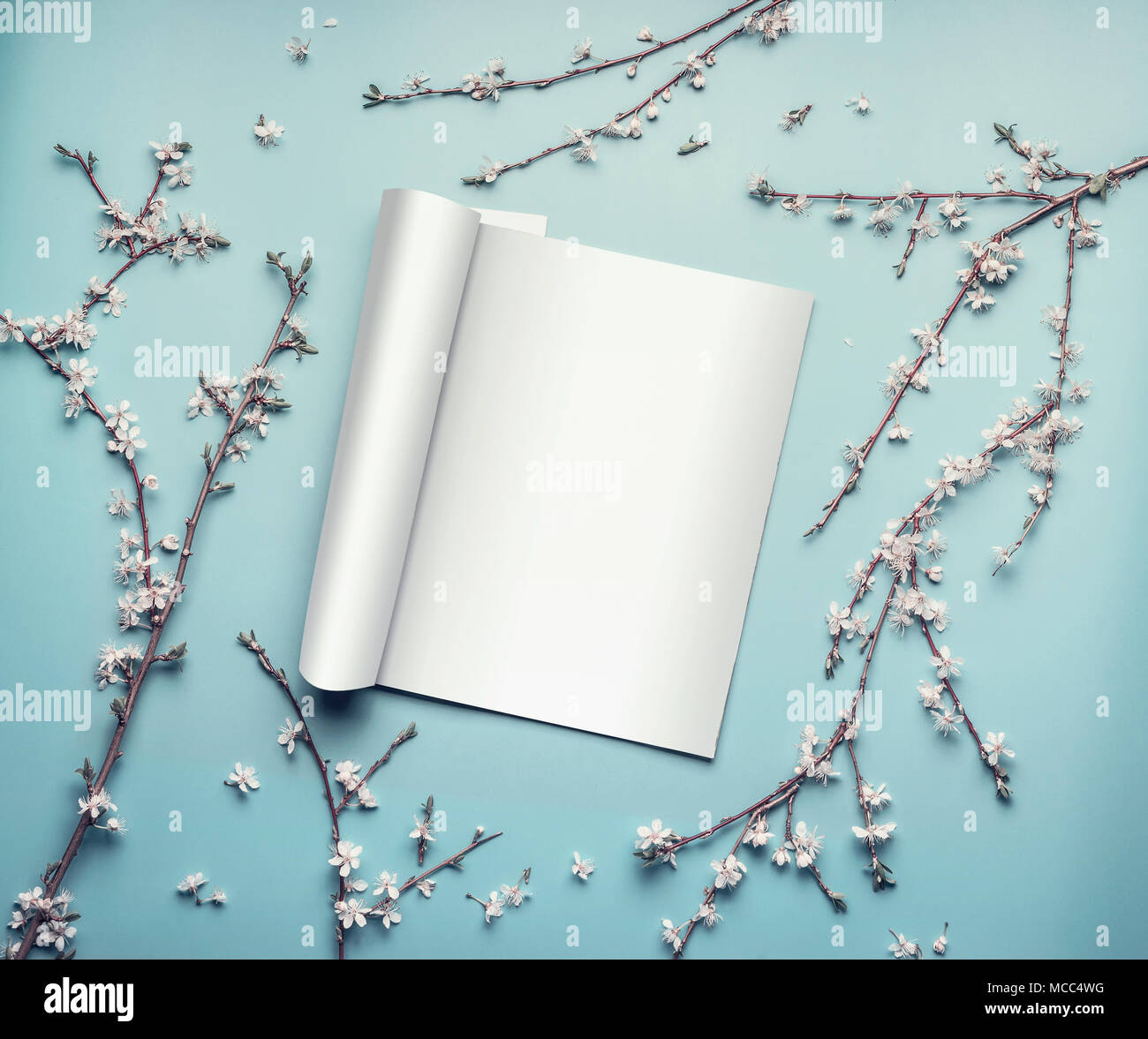 Mockup of open magazine or catalog on pastel blue desktop with twigs