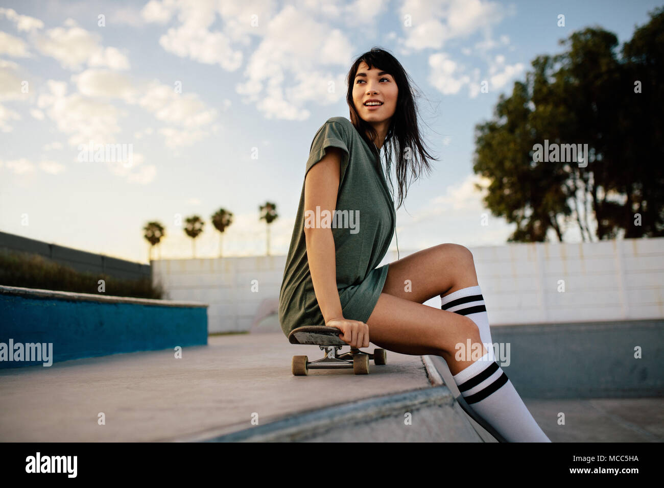 Beautiful skateboarder sitting on skateboard. Urban girl relaxing at skate park Stock Photo Alamy
