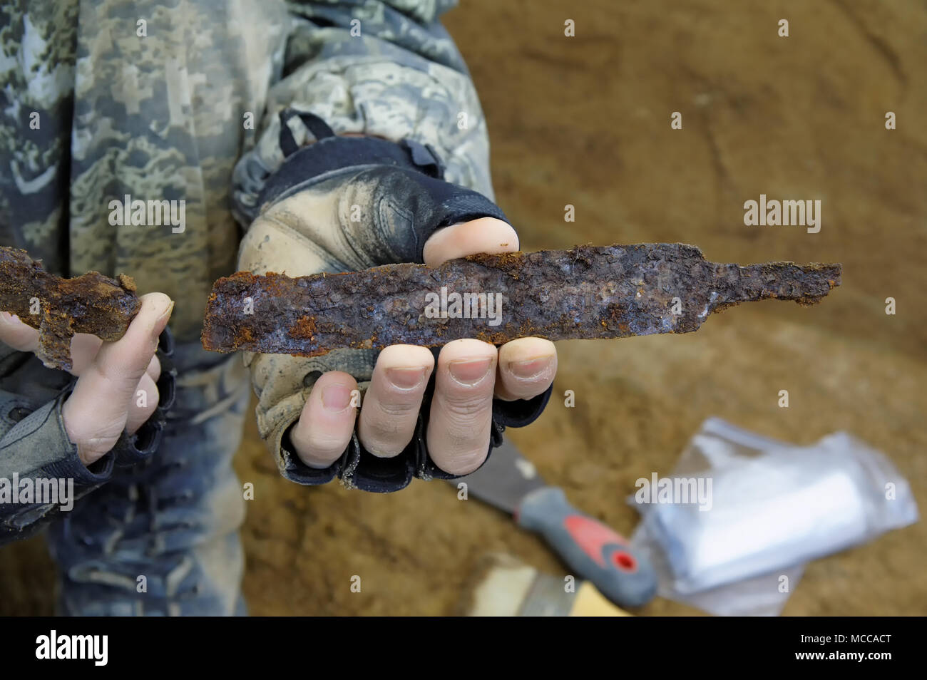 The hands of the archaeologist show a broken bronze knife from a medieval tomb Stock Photo