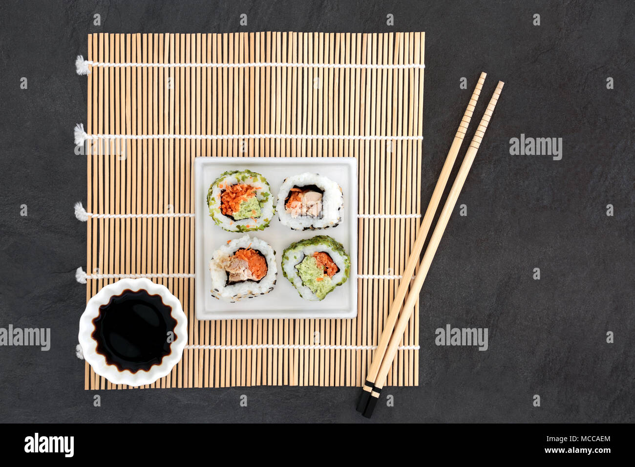 Japanese sushi and soy sauce with chopsticks on a bamboo mat on slate