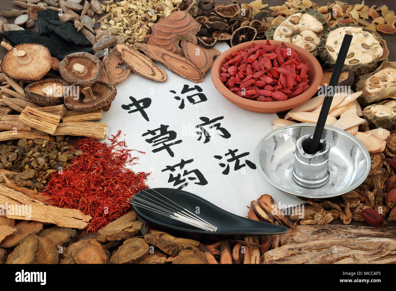Chinese acupuncture needles and moxa sticks used in moxibustion therapy with herbs used in herbal medicine and calligraphy script on rice paper. Trans Stock Photo