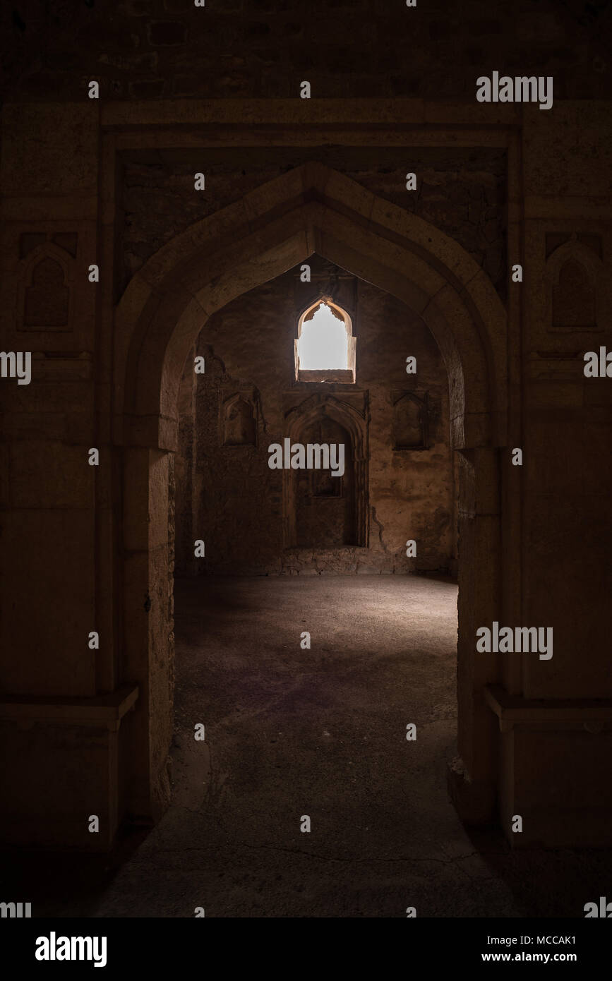 Mandu India, afghan ruins of islam kingdom, palace interior, mosque monument and muslim tomb. Sunshine from door in dark corridor. Stock Photo