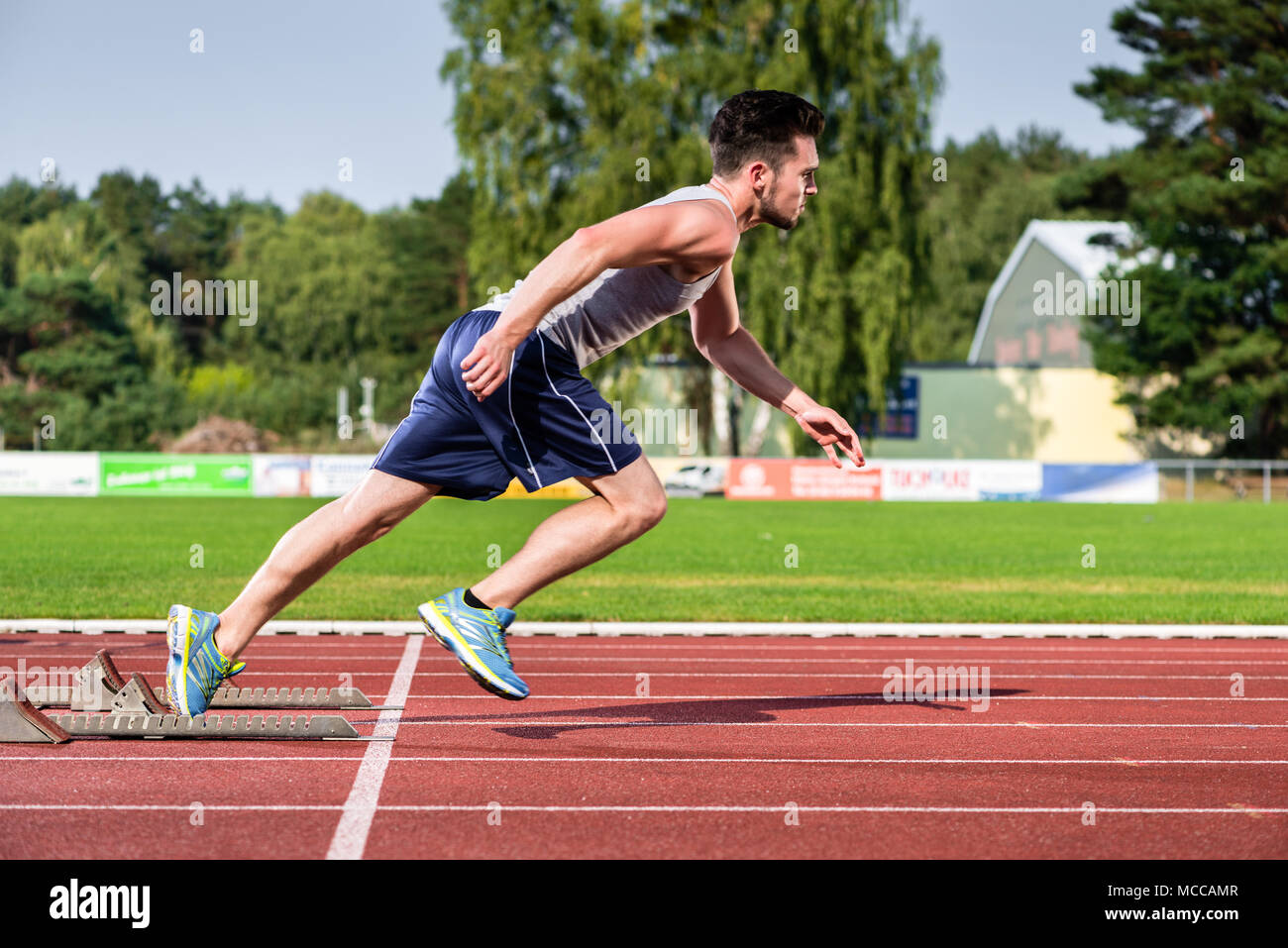 Athlete on cinder track of sports facility starts to sprint Stock Photo