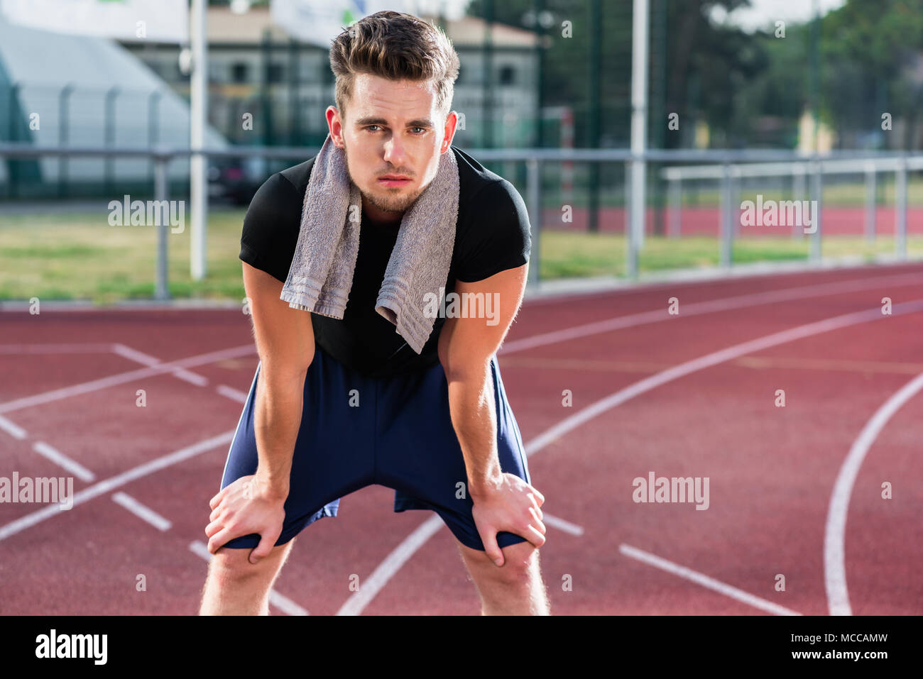 Athlete stretching on racing track before running Stock Photo