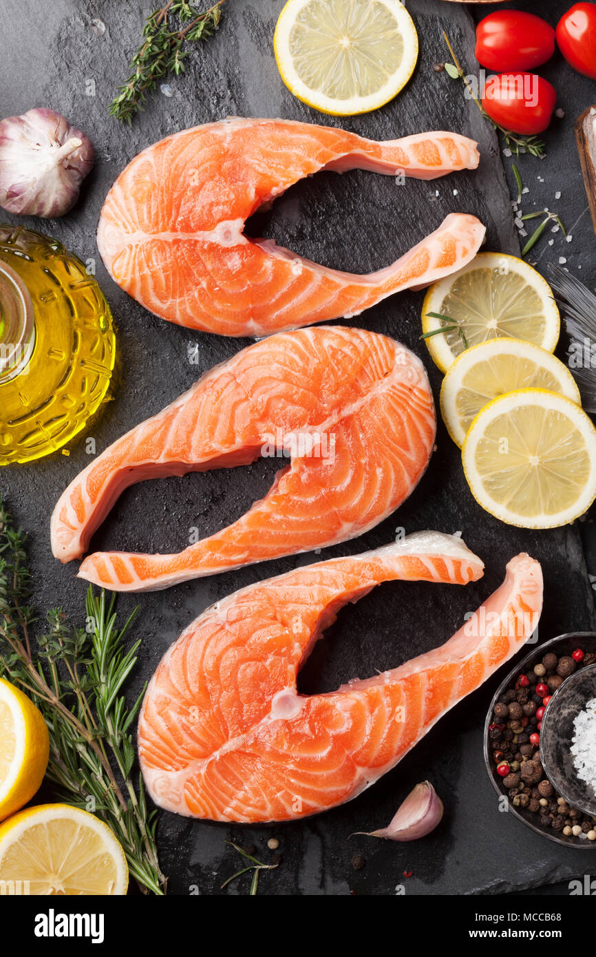 Raw salmon fish steaks with spices cooking on cutting board. Top view ...