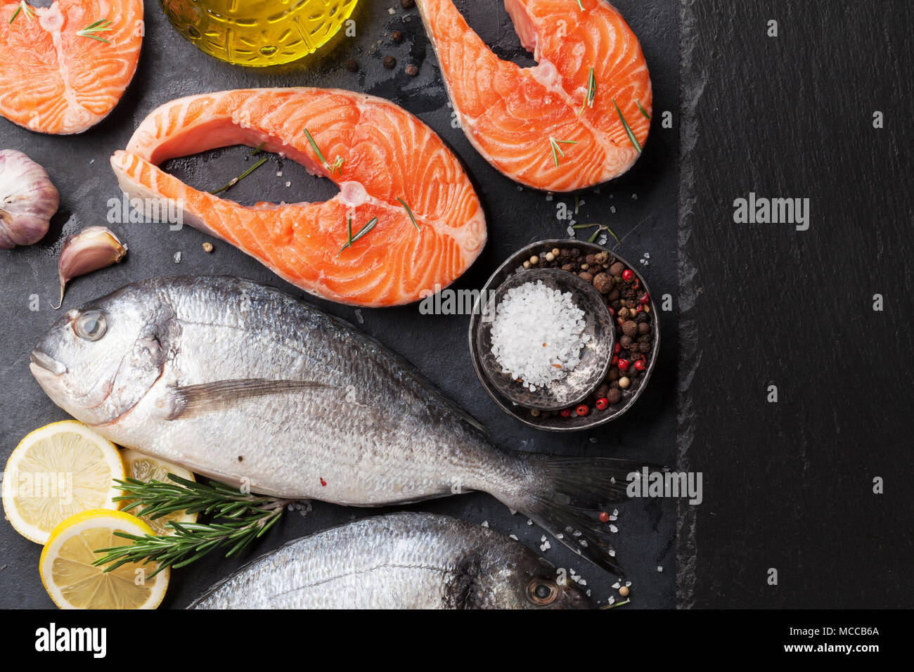 Raw salmon fish fillet and dorado with spices cooking on cutting board ...