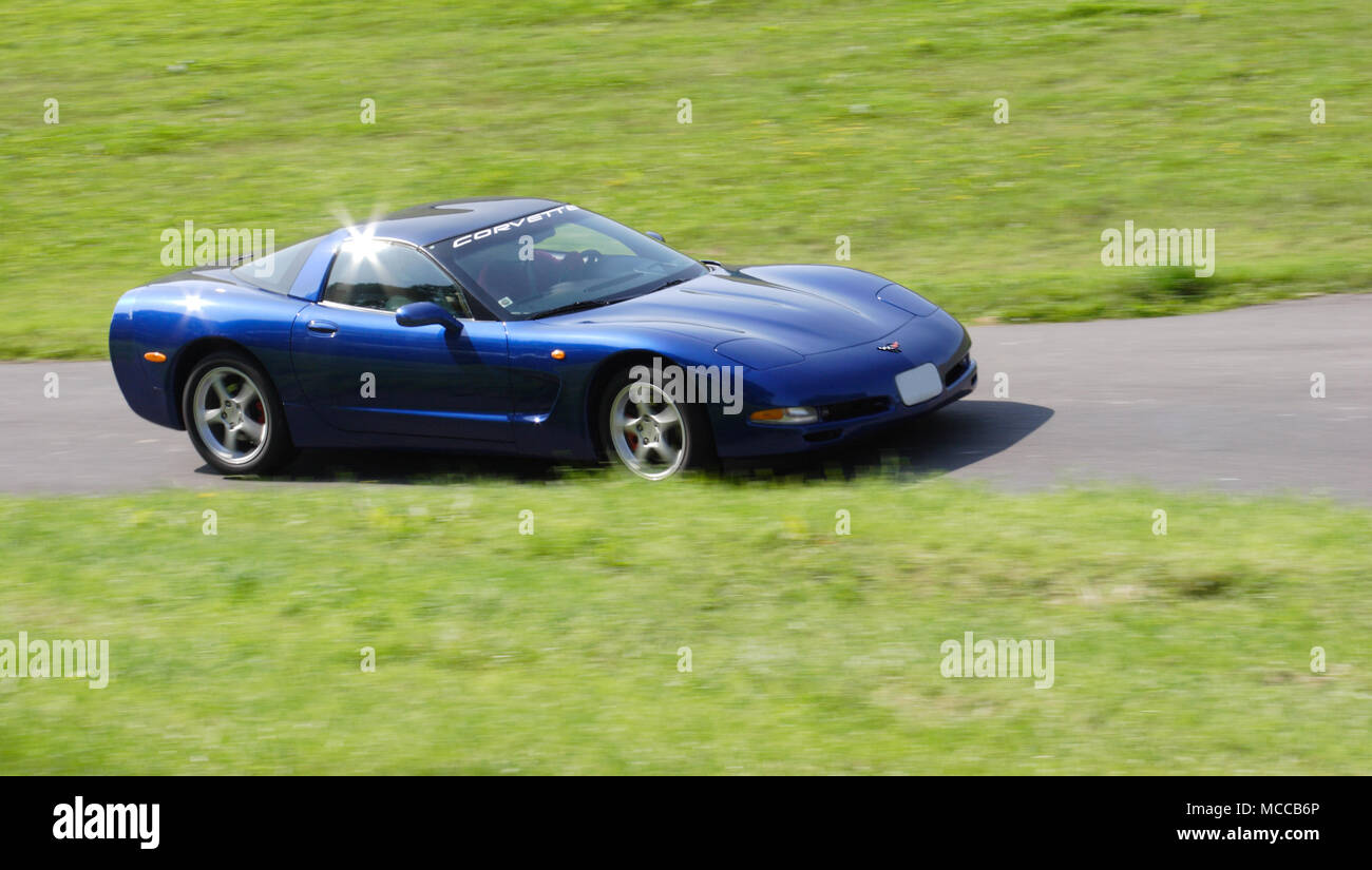 Blue Chevrolet Corvette driving fast on a country road. Stock Photo