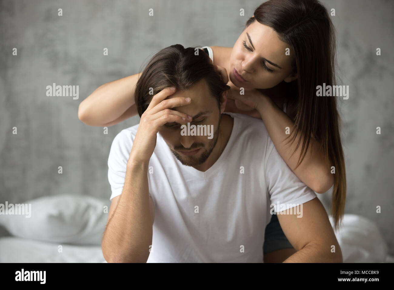 Caring woman embracing upset offended man trying to make peace cheer him up, loving wife apologizing resentful husband after conflict excusing asking  Stock Photo