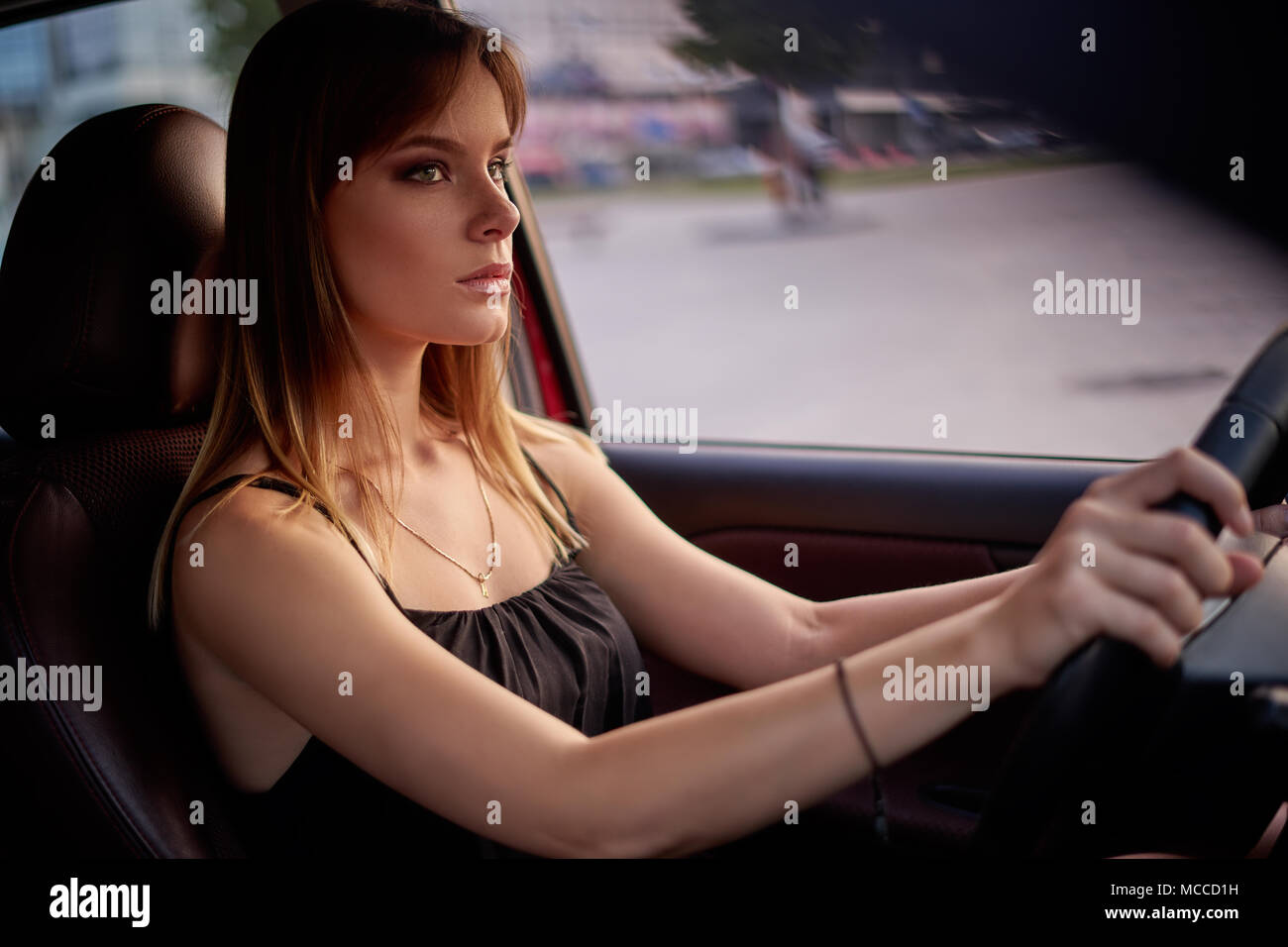 Beautiful serious girl sit in a car at twilight Stock Photo