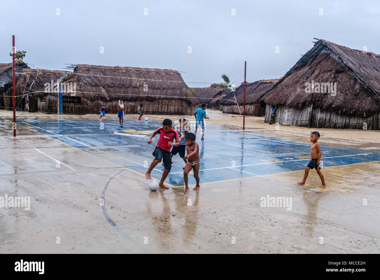 Guna Yala, Panama - march 2018: Group of boys playing soccer on sports court in Kuna Village on a rainy day - San Blas Islands Stock Photo