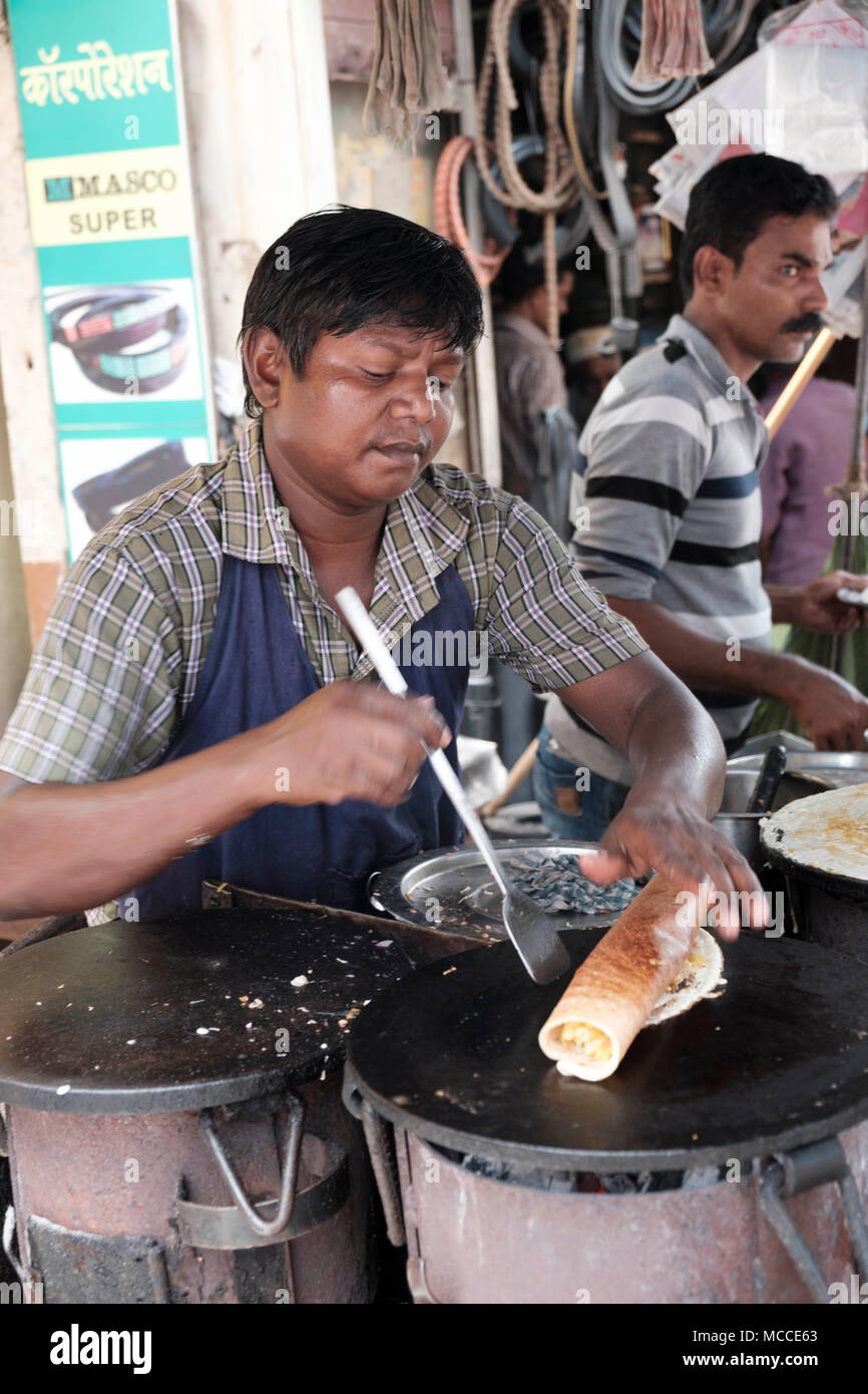 Cook making Masala Dosa on an outdoor hot plate in a Mumbai market Stock Photo