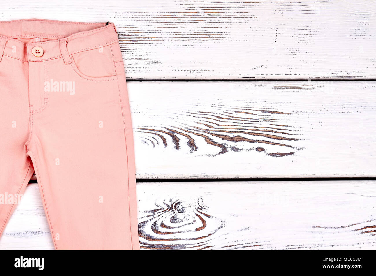 Teen girl peach color trousers. Girls colored summer skinny pants on wooden  bacground, copy space. Light cotton pants on white wooden background Stock  Photo - Alamy
