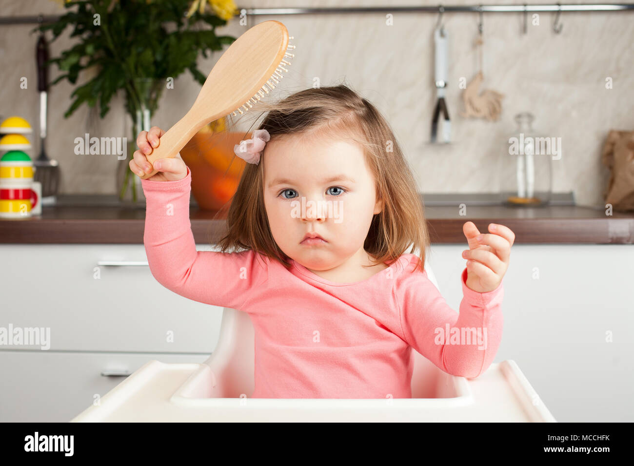 girl 2 years playing with a comb at home learning to comb her long