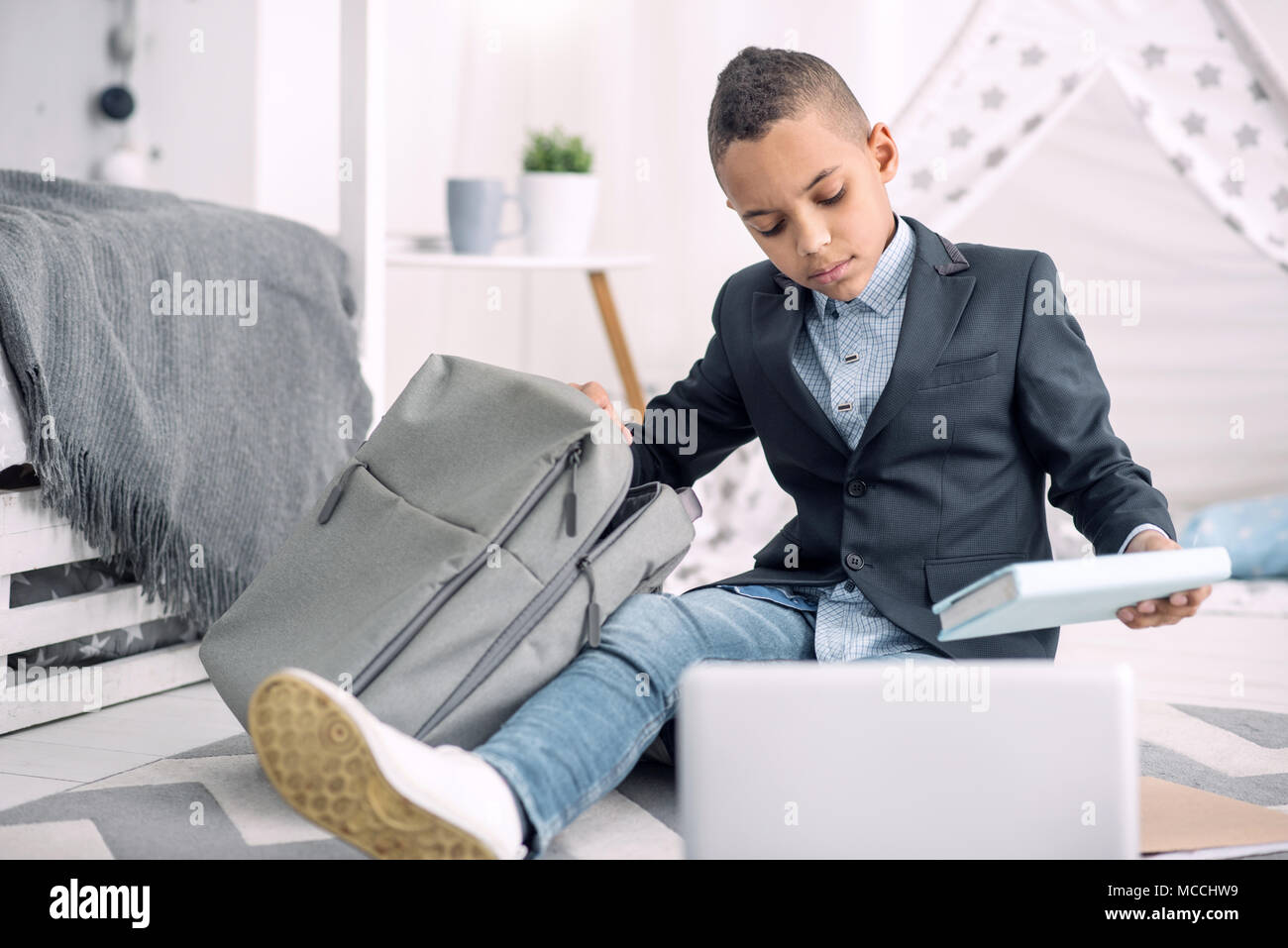 Attentive little boy packing notebooks Stock Photo