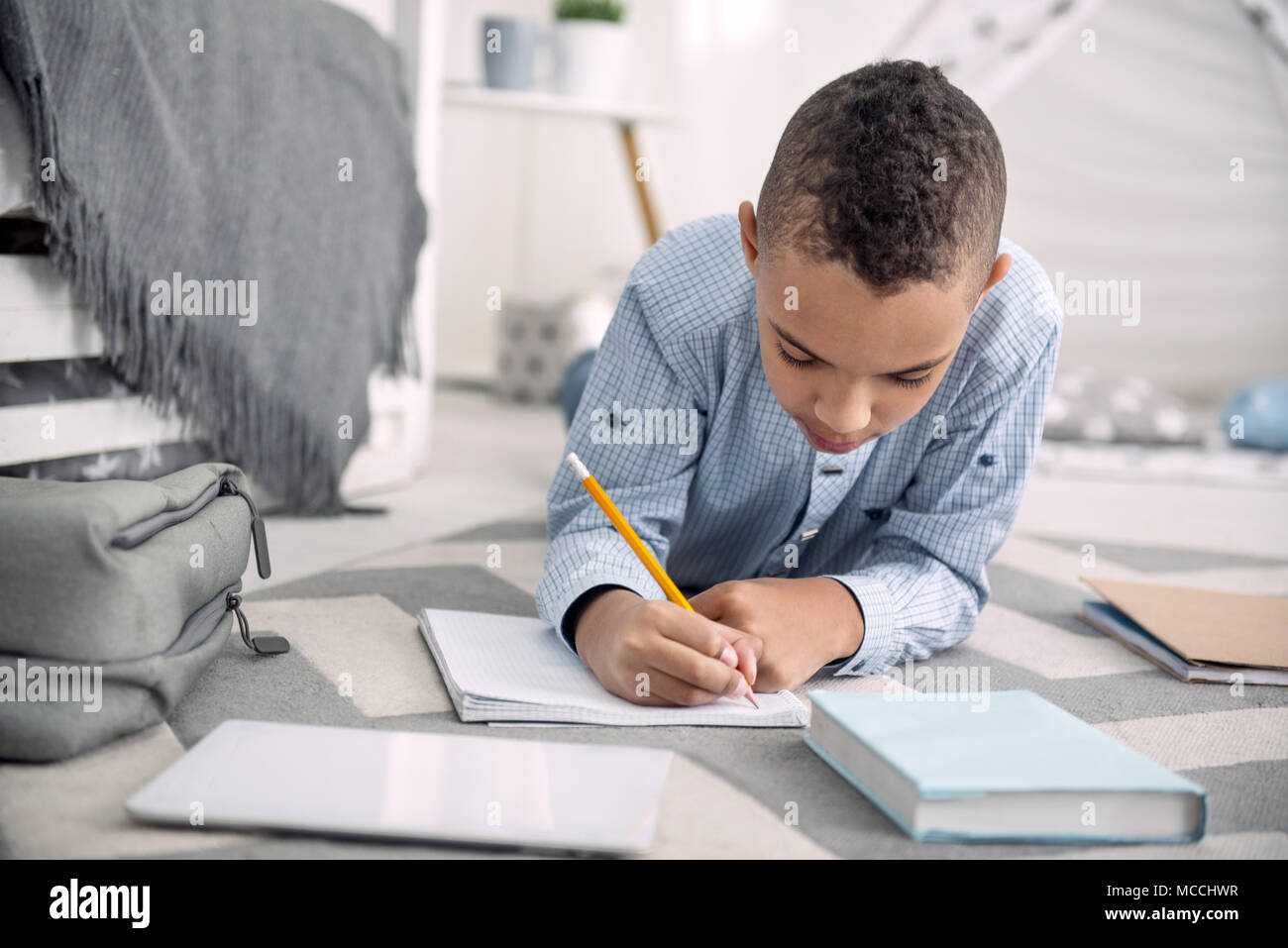 Attentive pretty boy writing down essay Stock Photo
