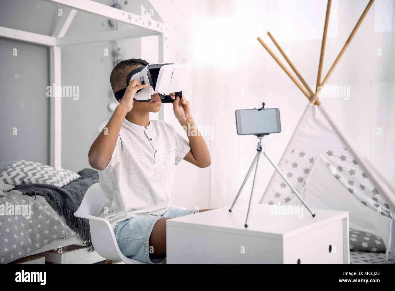 Serious boy blogger experimenting with VR headset Stock Photo