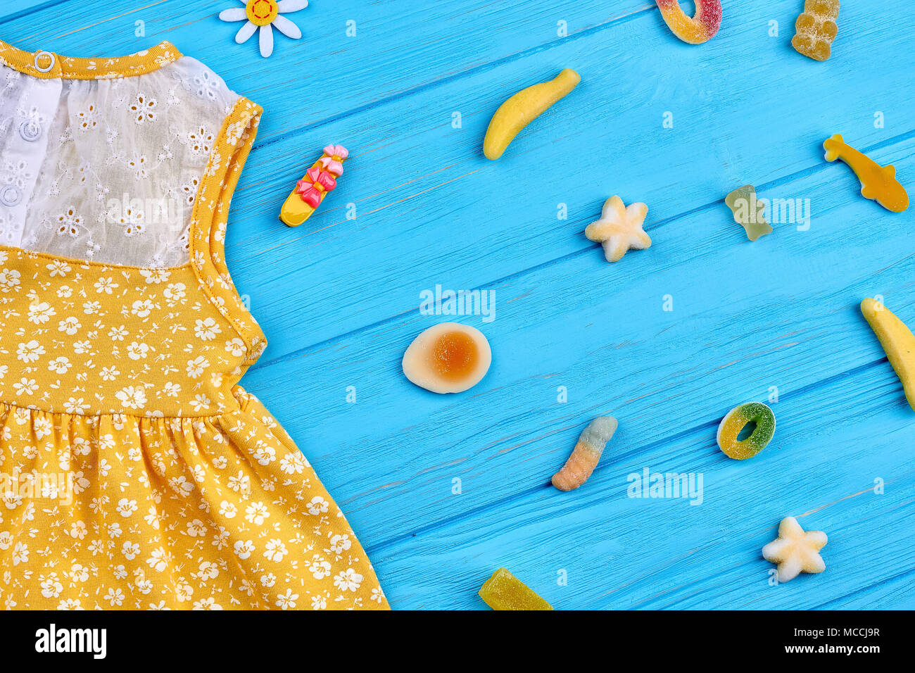 Yellow little dress and sweets close up. Colorful jelly beans and kids