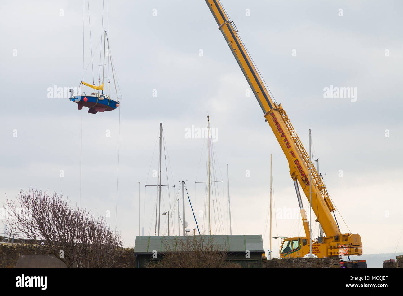 A large portable crane lighting a boat high in the sky, Fife, Scotland. Stock Photo