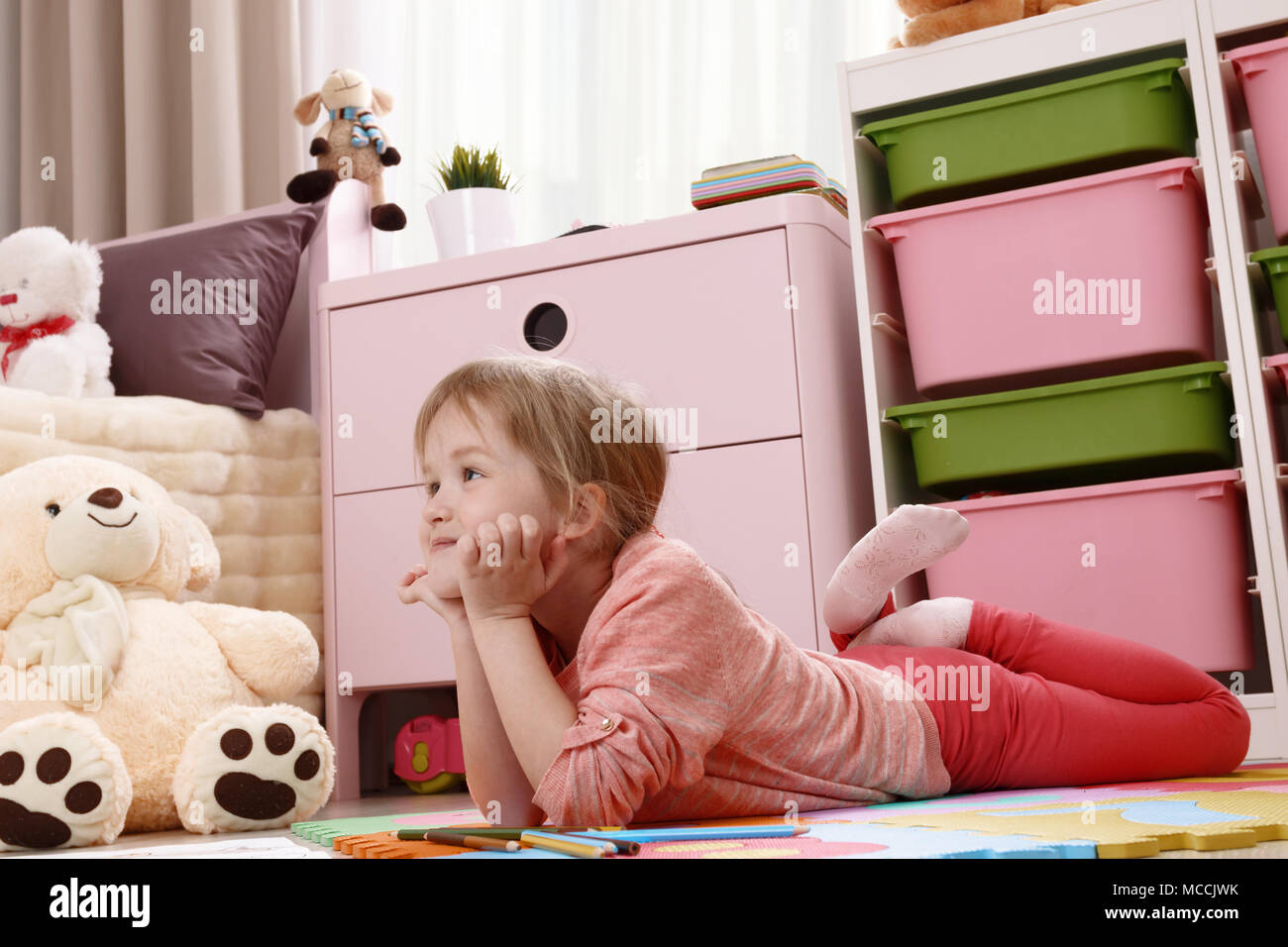 Cute little girl dreaming lying on the floor in the children's room