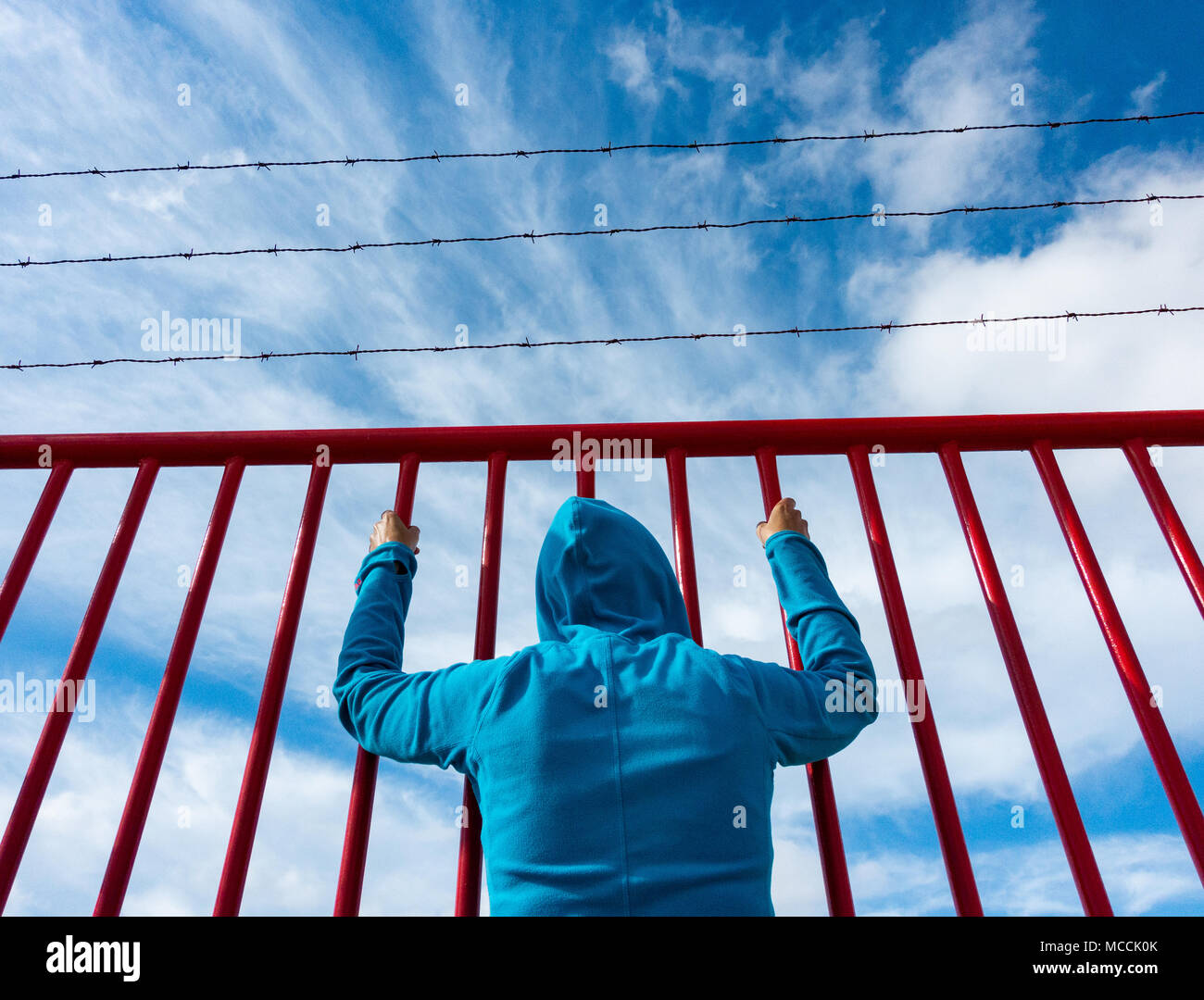 Woman behind bars topped with barbed wire: asylum,refugee,prison,detention,brexit, borders... concept image Stock Photo