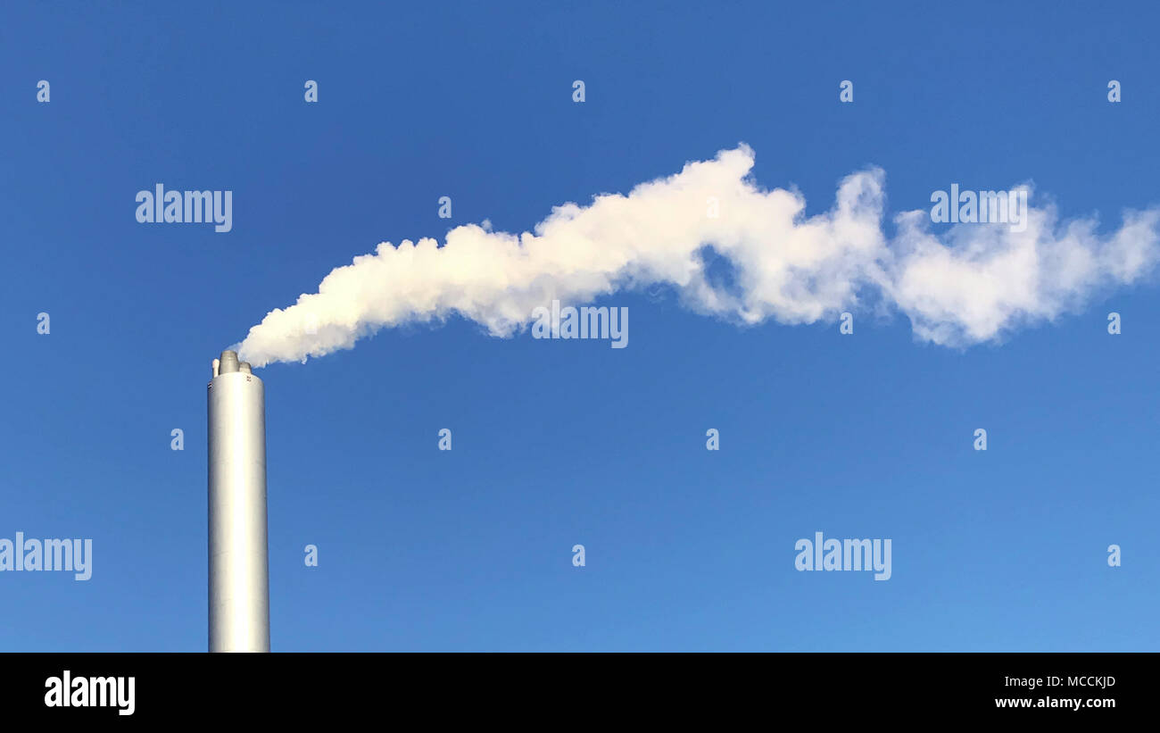 Cloud of white smoke from industrial chimney against blue clear sky