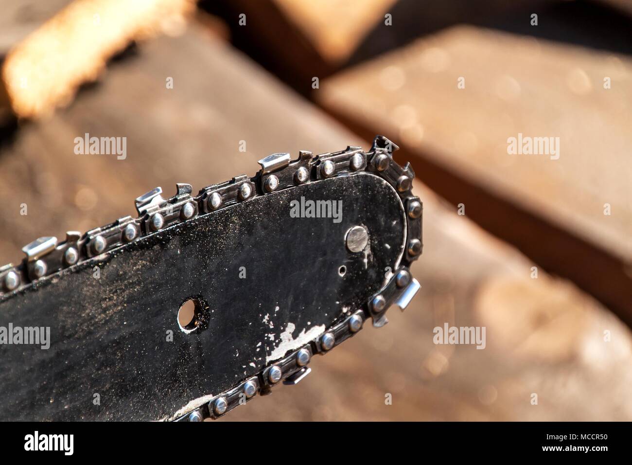 Closeup view of a chainsaw bar and cutting chain. Dirty blade of a chainsaw. Blade of a chainsaw in the garden, copy space Stock Photo