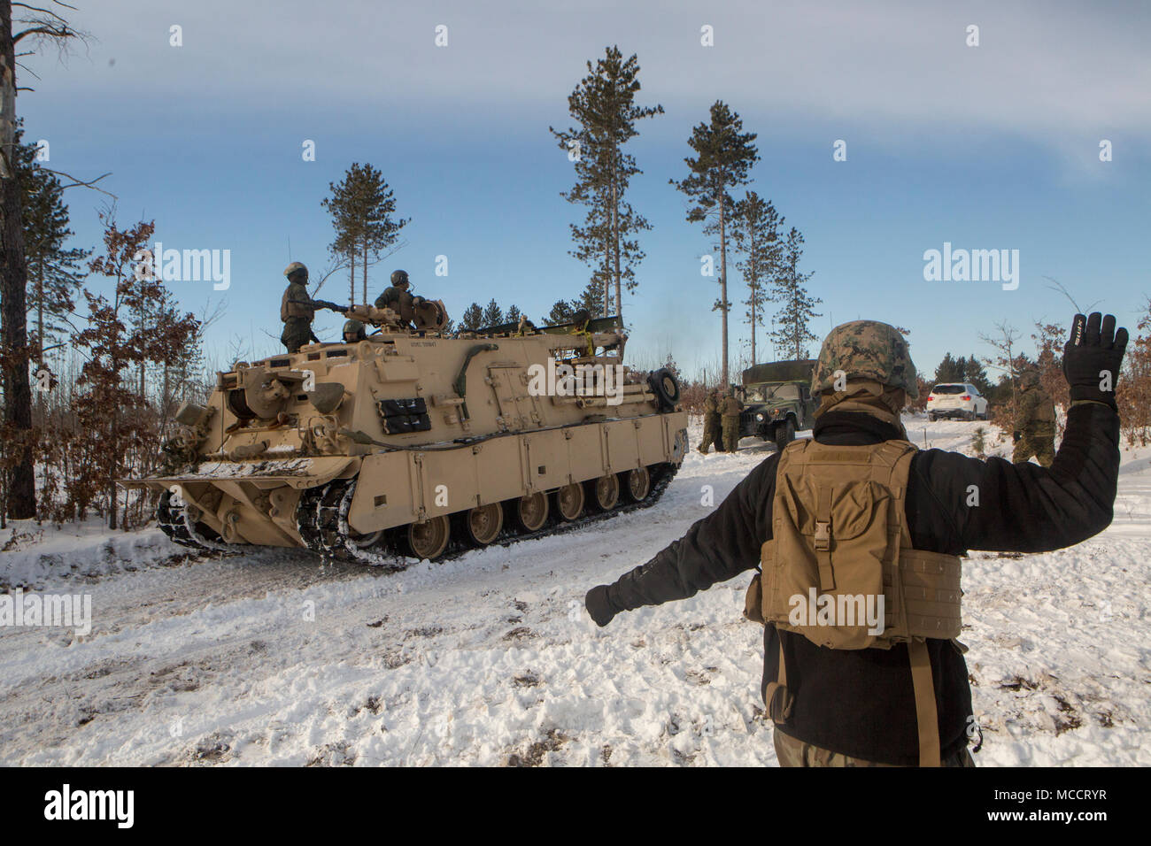 A Marine with Company F, 4th Tank Battalion, 4th Marine Division, ground guides an M88 recovery vehicle to a fuel resupply station during exercise Winter Break 2018, near Camp Grayling, Michigan, Feb. 10, 2018. Winter Break 18 allows the Marines of Fox Co. to develop essential mechanized infantry tactics and offensive and defensive capabilities in an austere cold weather environment. Stock Photo