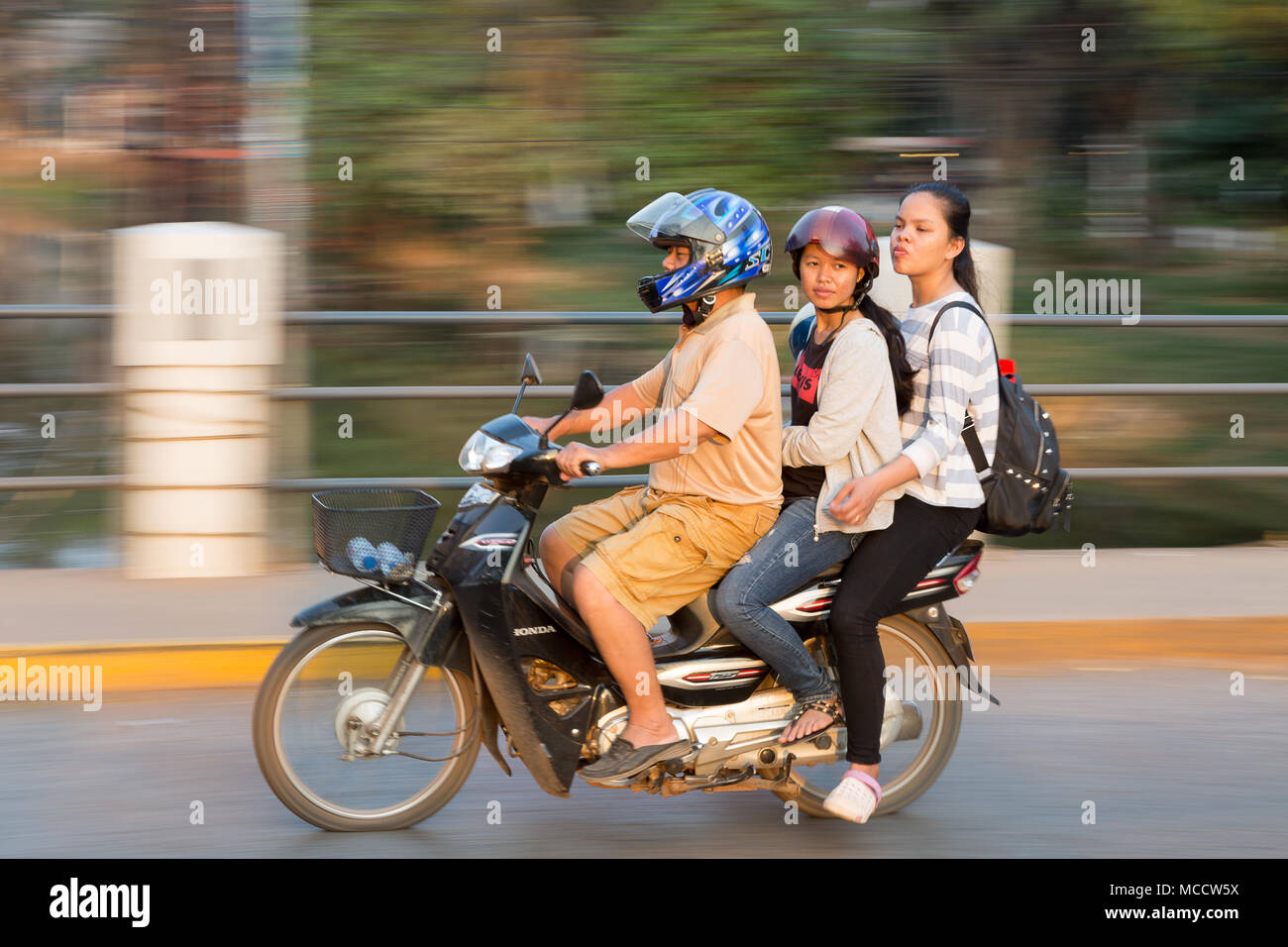 panned motion photo of three people riding on a motorbike, Siem Reap, Cambodia, Asia - Stock Photo