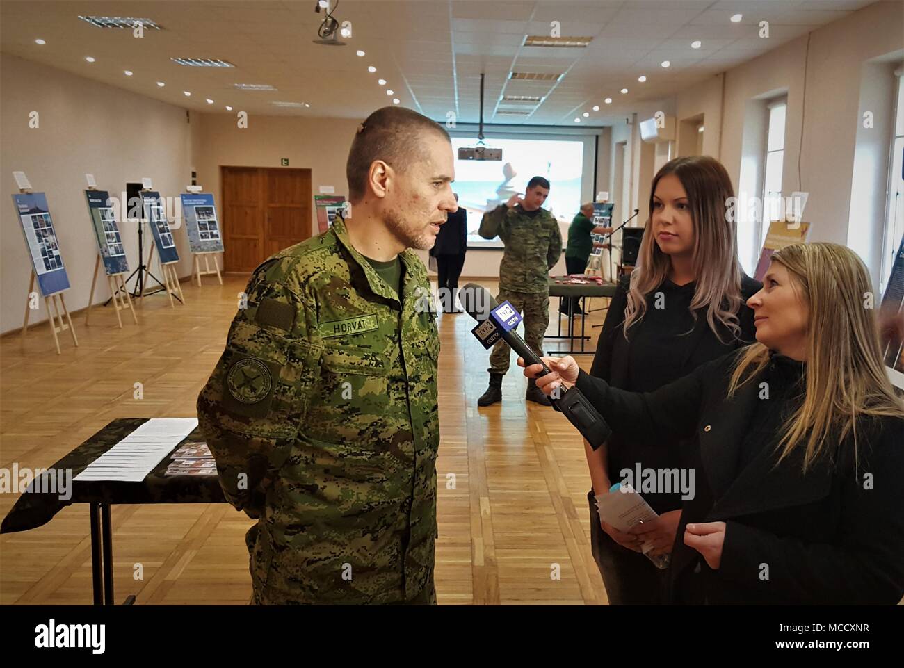 Croatian Army Capt. Slaven Horvat, assigned to the Croatian Volcano Battery and Battle Group Poland conducts an interview with Polish media TVP3 explaining the Croatian cultural heritage events, Sylwia Pindor (center) serves as linguist during the interview at the Polish 15th Mechanized Brigade headquarters Giżycko, Poland, Feb. 12, 2018. The celebration allowed the ambassador to express gratitude to Polish leaders and shared Croatian culture with the community leaders in attendance. The unique, multinational battle group is comprised of U.S., U.K., Croatian and Romanian soldiers serve with th Stock Photo