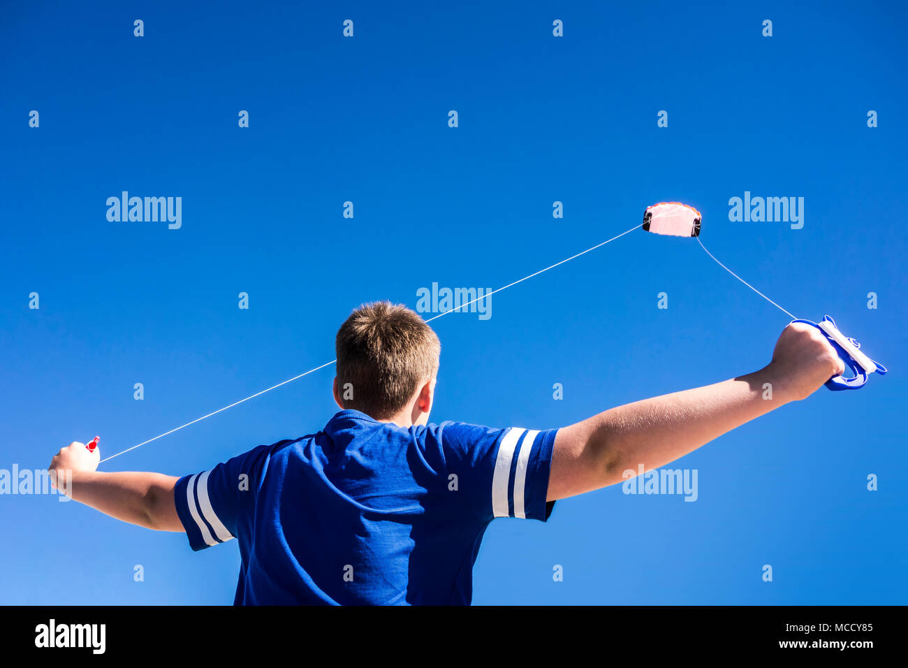Child flying a kite in the clear blue sky. Stock Photo