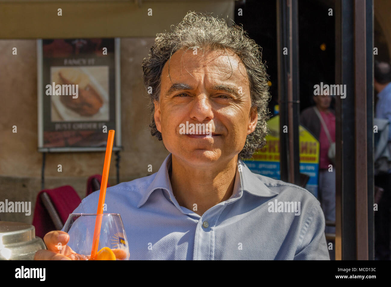 middle aged tanned male tourist enjoys his vacation in Prague relaxing while drinking cocktail Stock Photo