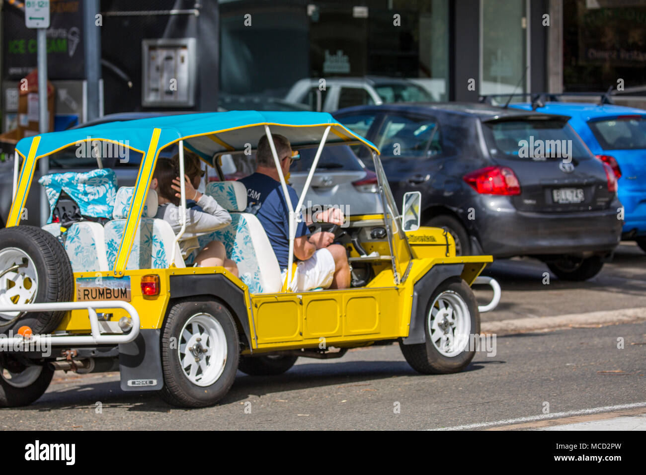 Yellow Mini Moke car vehicle in Sydney Australia carrying a family Stock Photo