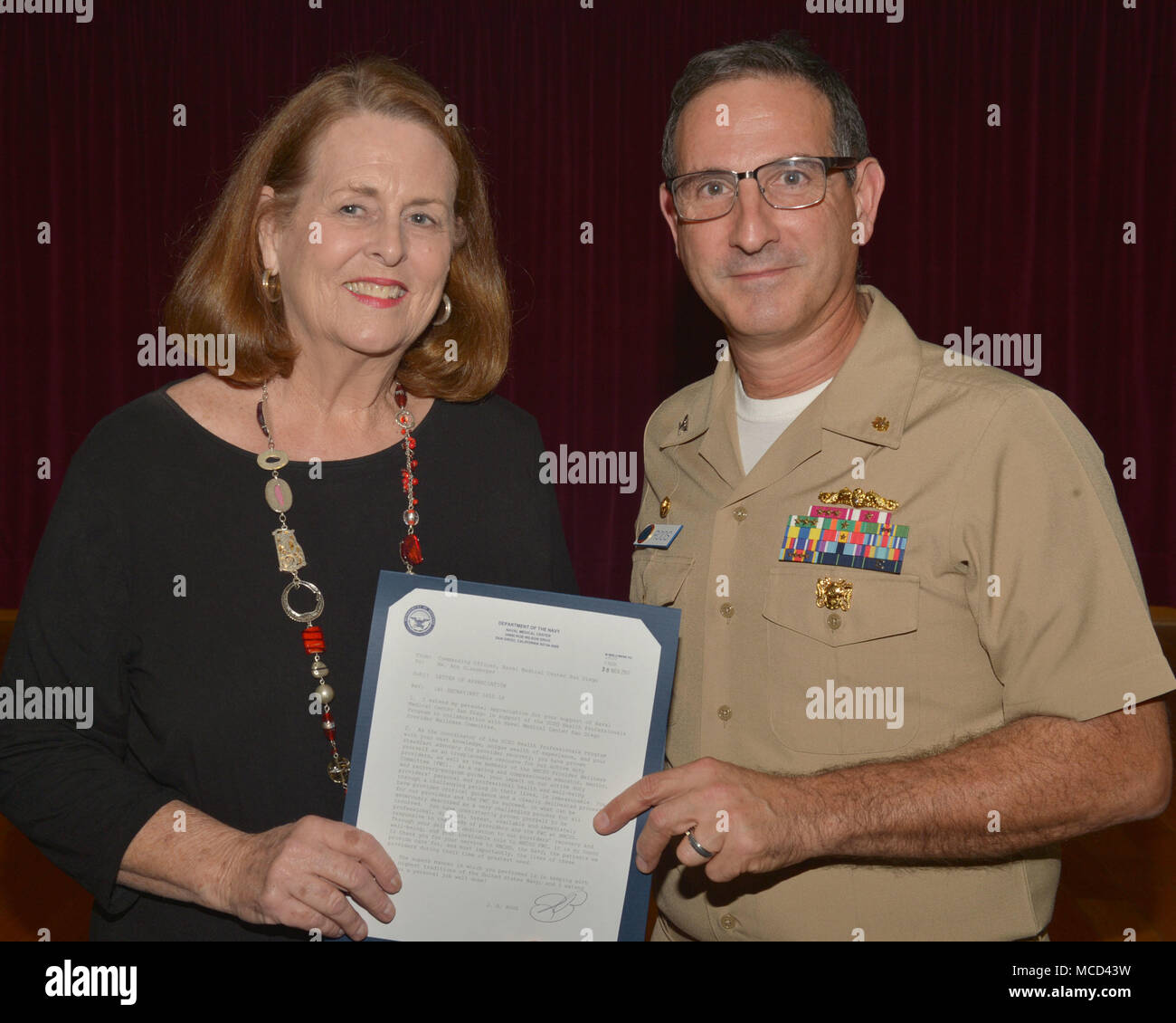 180214-N-PN275-1001 SAN DIEGO (Feb. 01, 2018) CAPT. Joel Roos, Naval Medical Center San Diego Commanding Officer, Presents Ann Glassmoyer, a Licensed Clinical Social Worker at University of San Diego with a Letter of appreciation for supporting the NMCSD wellness committee. The NMCSD Wellness Providers are an integral piece of patient safety commitment at the hospital. (U.S. Navy Photo by Mass Communication Specialist 2nd Class Zachary Kreitzer) Stock Photo