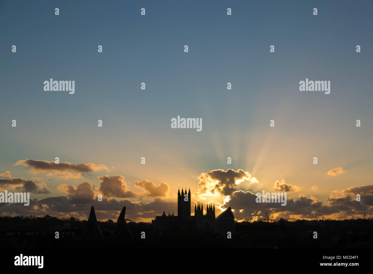 Crepuscular rays at dawn rising from a cloud above Canterbury Cathedral, Kent, UK. Stock Photo