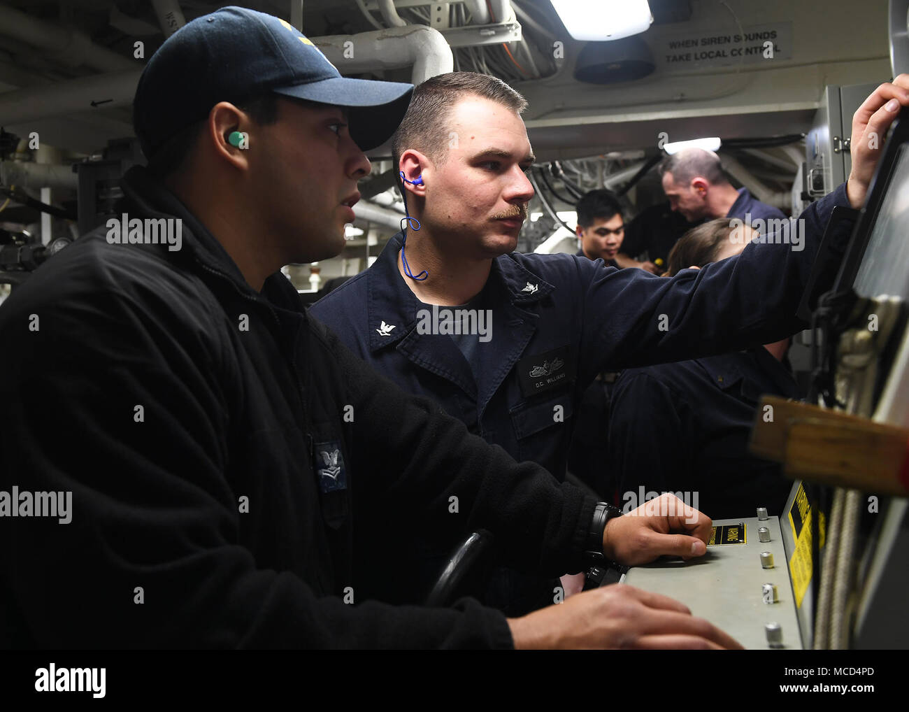 180214-N-FN963-0065 PACIFIC OCEAN (Feb. 14, 2018) Electronics Technician 2nd Class Brian Benavides, left, from Corpus Christi, Texas, and Interior Communications Electrician 3rd Class Daniel Williamson, from Jacksonville, Fla., perform system checks during an engineering drill aboard the Arleigh Burke-class guided-missile destroyer USS Sterett (DDG 104). Sterett is on a scheduled deployment to conduct operations in the Indo-Pacific region. It will also support the Wasp Expeditionary Strike Group (ESG) in order to advance U.S. Pacific Fleet’s Up-Gunned ESG concept and will train with forward-de Stock Photo