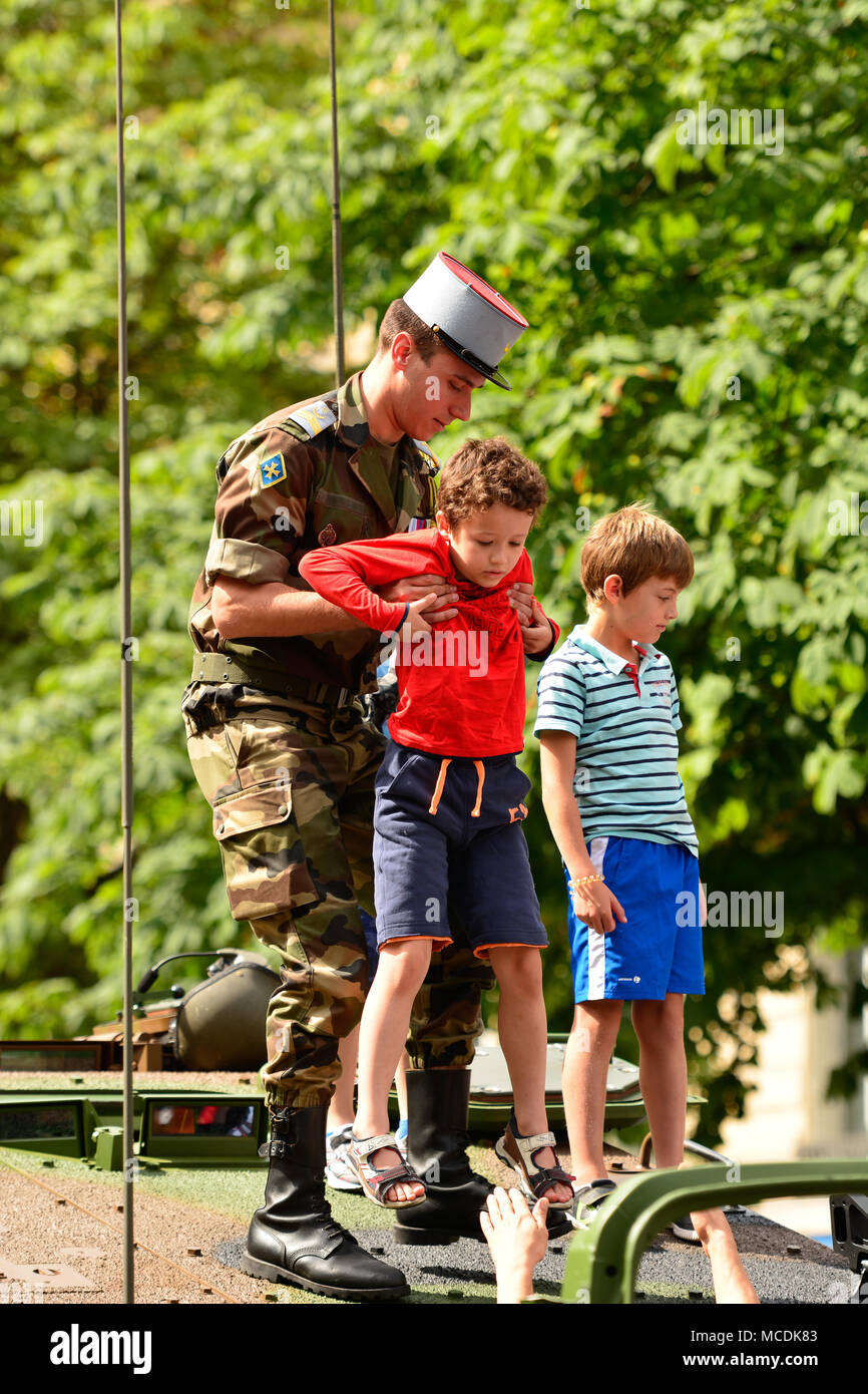 A French soldier helps a child get off the top of a military tank ...
