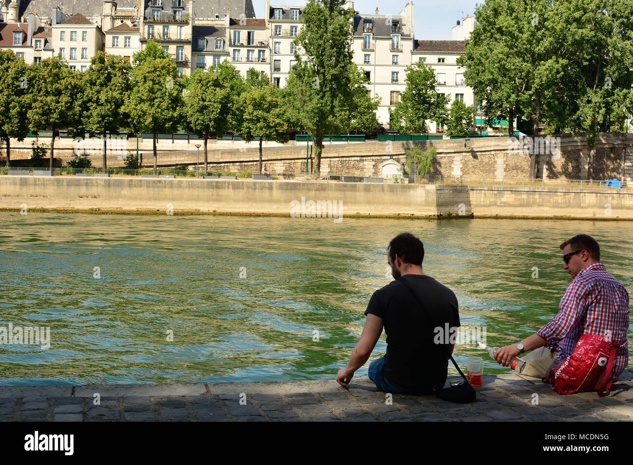 A Man Pours A Drink For A Friend As They Sit On The Bank Of The River Seine In Paris France Stock Photo Alamy