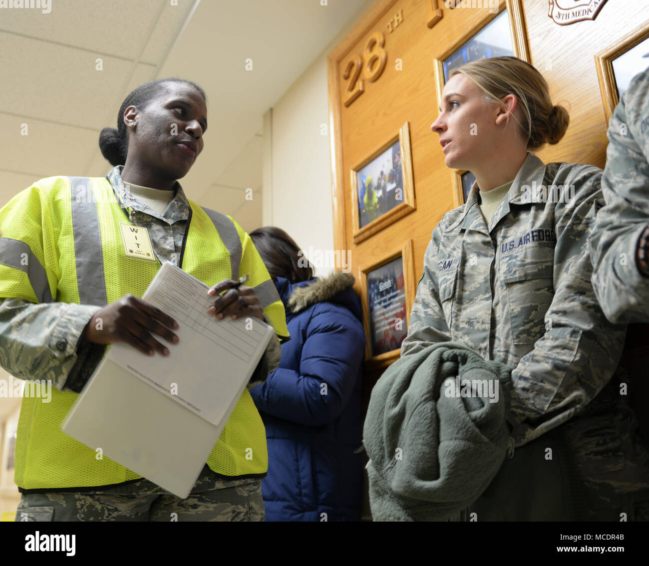 Master Sgt. Jvalyn Vaughn, a wing inspection team member, talks to Senior Airman Chelsea Deegan, a 28th Medical Operations Squadron aerospace medical technician, during an active shooter exercise inside the 28th Medical Group at Ellsworth Air Force Base, S.D., Feb. 22, 2018. Ellsworth AFB conducted an active shooter exercise, testing Airmen in nearly 20 locations on their ability to respond to different situations in their buildings. (U.S. Air Force photo by Senior Airman Michella Stowers) Stock Photo